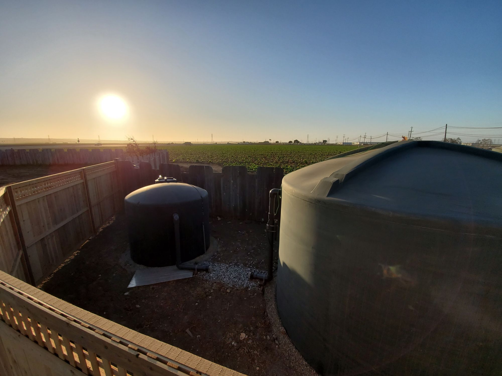 Water tanks beside farm fields at sunset