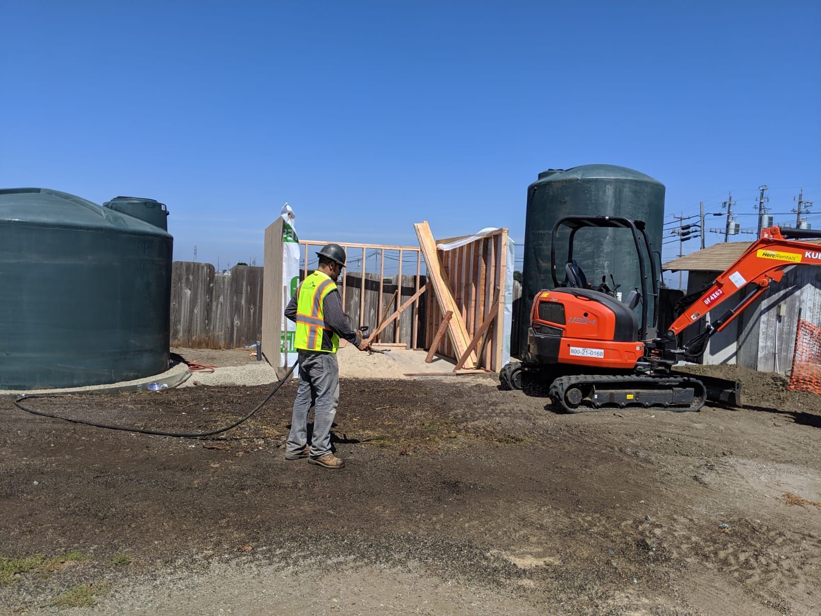 A worker framing the treatment building beside the tanks