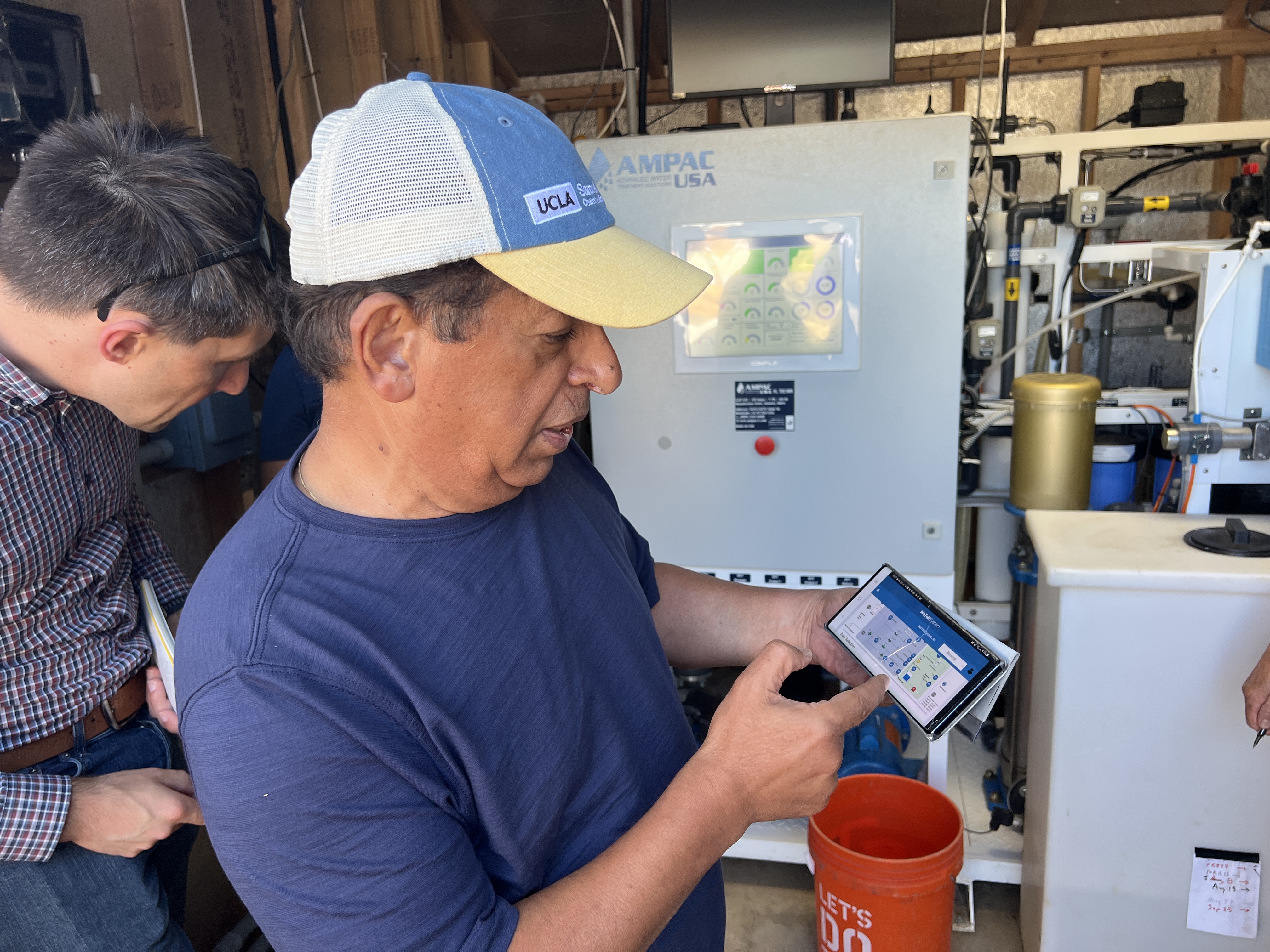 Professor Yoram Cohen of UCLA demonstrating remote monitoring of the system on a tablet, with a colleague looking on